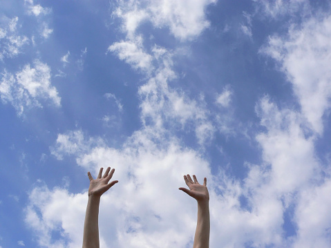 Two children's hands are stretched to the sky