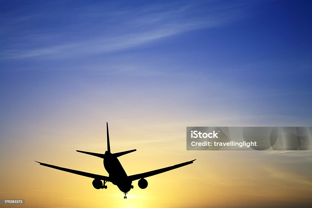 Jet avión aterrizaje de silueta al atardecer azul amarillo espacio de copia - Foto de stock de Aire libre libre de derechos