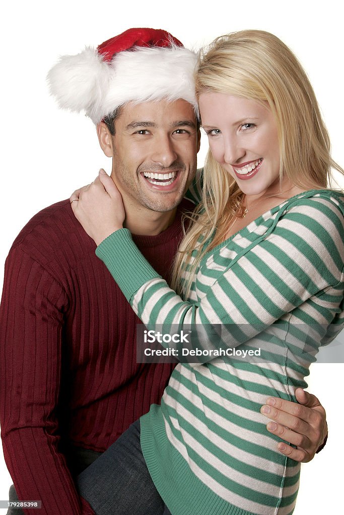 Christmas Couple An attractive young couple with the Christmas Spirit.  A blonde woman wearing green and white sits playfully on the lap of a dark-haired man wearing a santa hat.  Both are laughing/smiling against a white background Beautiful People Stock Photo