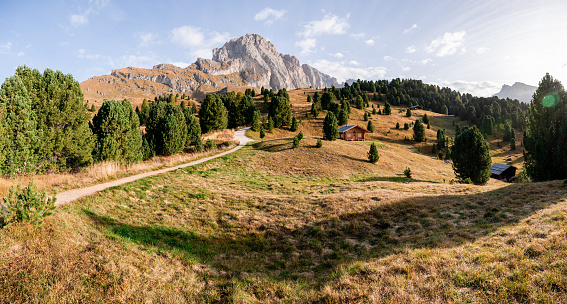 Val Gardena, Alto Adige, Italy - October 10, 2023: Sweeping panoramic views towards the Fermeda peaks of the Odle or Geisler mountain range. To the left of the mountains sits the popular Seceda ridgeline. Huts are visible on the slopes. Autumn is a busy time for hiking tourists before the skiing season starts.