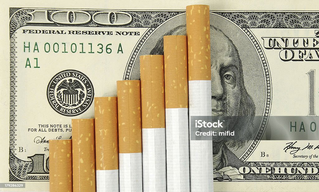 cigarettes the cigarettes laying on american money.  Cost of a bad habit. Cigarette Stock Photo