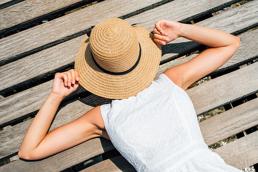 Beautiful girl covers her face from sun with a hat