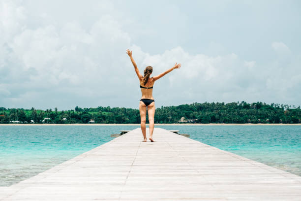 istock Woman in bikini walking down a tropical jetty 1792867223