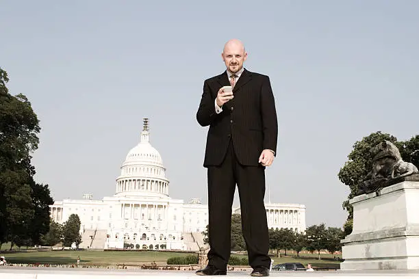 Photo of Caucasian Businessman Checks Email Outside U.S. Capitol, Washington DC