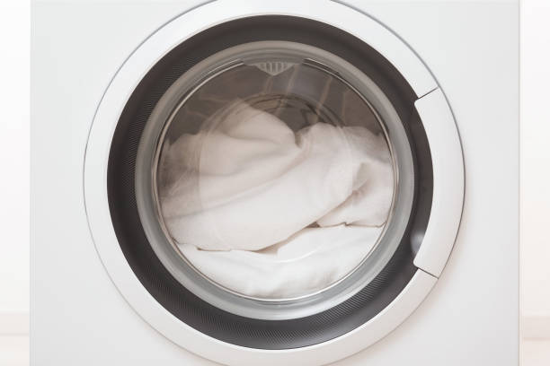 istock Closed washing machine full of white clothes. Closeup. Front view. 1792882922
