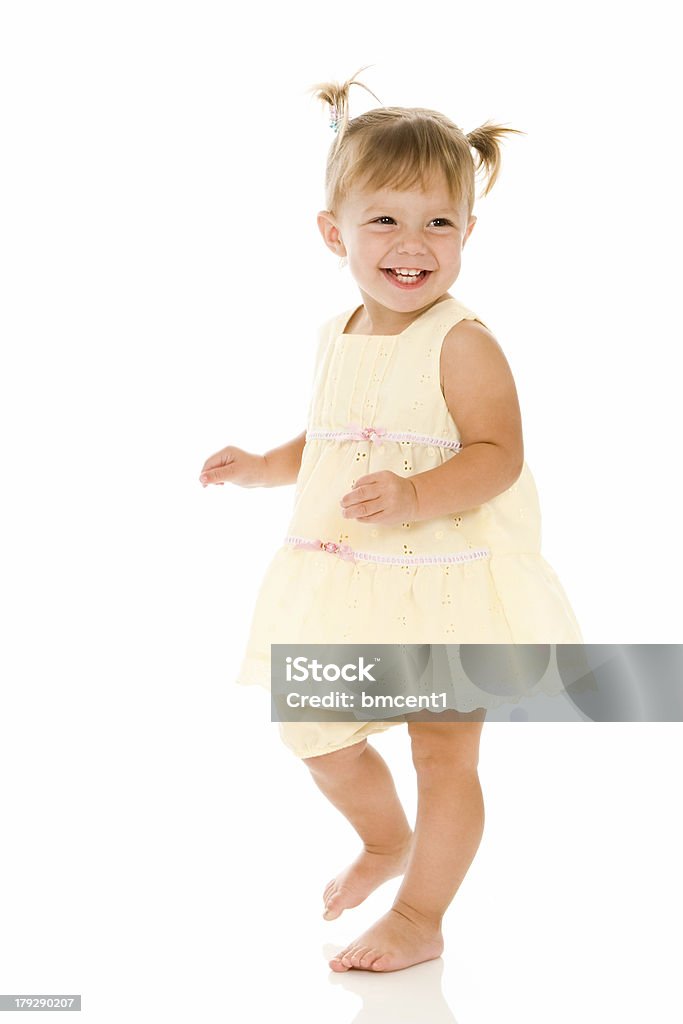 Smiling Dancing Toddler Girl Happy toddler girl wearing yellow dress and pig tails in her hair is having a great time dancing in the studio. Isolated on white. Toddler Stock Photo