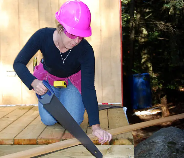 female carpenter/construction worker saws wood