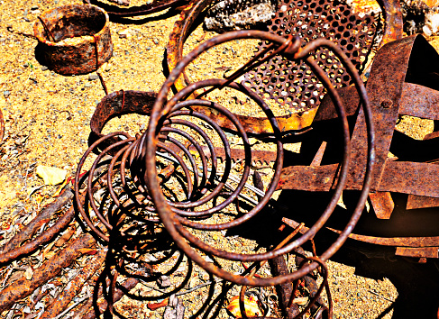 A collection of rusted metal objects, entangled in a disarray of decay, showcases the natural process of oxidation over time, juxtaposing the permanence of metal with the inevitability of corrosion. A tangle of once-functional metal pieces lies in a quiet heap, each item cloaked in the distinctive, textured hues of rust that only time can paint. These remnants, which include coiled springs, weathered gears, and other mechanical parts, tell a silent story of their former utility and the inexorable wear of years. The image captures not just the physical decay but also the beauty in the breakdown, highlighting the contrast between the enduring strength of the metal and its ultimate surrender to nature's patient artistry of oxidation. This scene is a testament to the cycles of use and disuse, an industrial elegy to the things we leave behind.