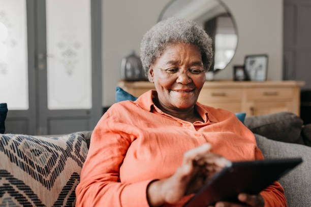 istock Front view of senior woman using digital tablet on sofa 1792968345