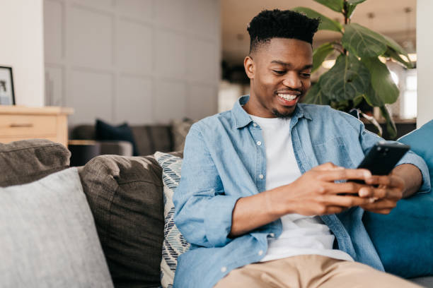istock Happy young man using cellphone on sofa at home 1792968602