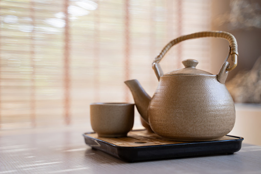 Teapot and tea cups, tea set on a tray placed on the table, blurred background, morning light.
