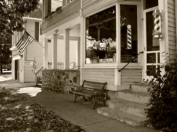 A small town barbershop with other storefront and flag in sepia tone