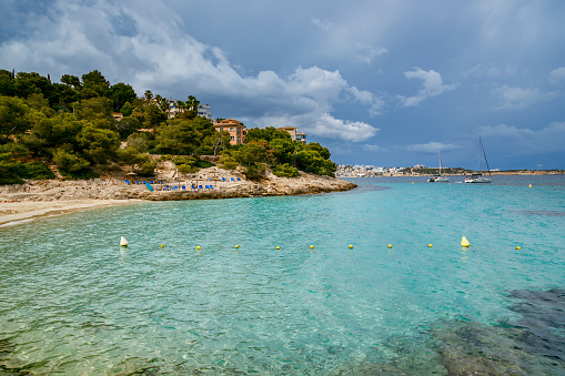 A little girl wearing a colorful lifebuoy bathes in the beautiful and colorful waters of the Mediterranean Sea on a summer day on the beach of Monti Russu in Santa Teresa Gallura, facing the Strait of Bonifacio.