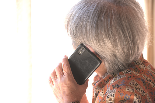 Rear view of a senior woman anxiously talking on the mobile phone
