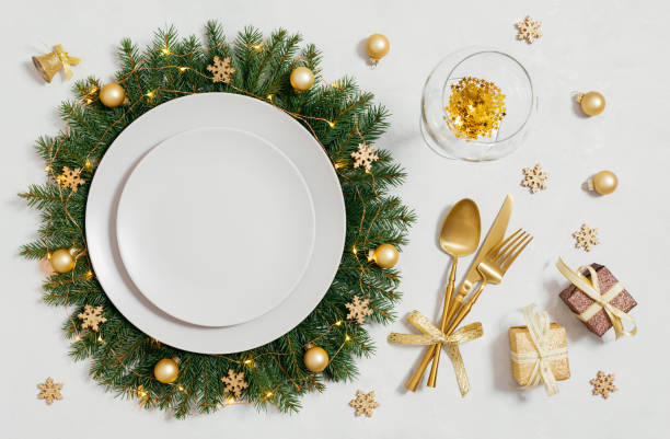 istock Christmas table setting with empty plate and gold accessories on white background. Plate in a Christmas wreath. New Year party. Top view, flat lay. 1793003347
