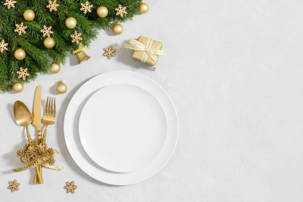 istock Christmas table setting with empty white plate and gold decor on a white background. New Year serving. Template for menu or design. Festive dinner. Copy space, top view, flat lay. 1793004965