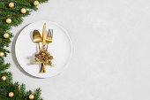 Festive table setting with Christmas decor and utensils, gold accessories on a white background. Preparation for Christmas dinner. Copy space, top view, flat lay.