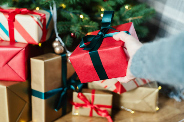 istock An unrecognizable female hand puts a gift under the Christmas tree. 1793006041