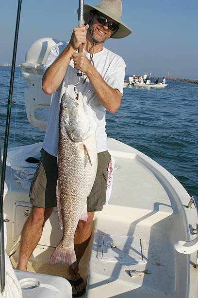 istock Happy fisherman hoists big redfish 179300802