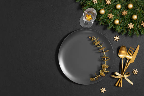 istock Christmas table setting with fir branches, golden decorations on black background. Empty black plate for design. Happy new year. Space for text. Top view, flat lay. 1793011776