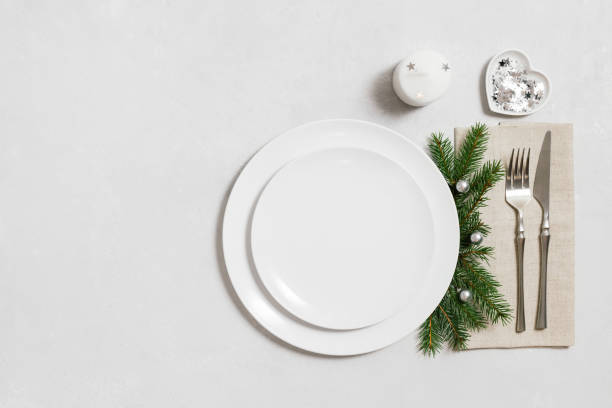 istock Christmas table setting with empty white plate and silver decorations. New Year serving on white background. Festive dinner. Copy space, top view, flat lay. 1793012334
