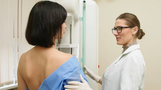 una dottoressa in una clinica moderna spiega la procedura mammografica a una paziente adulta in topless che si sottopone a una mammografia. una donna sana è impegnata nella prevenzione del cancro in un reparto ospedaliero. - doctor radiologist computer latin american and hispanic ethnicity foto e immagini stock