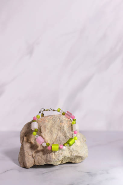 buntes edelsteinschmuckarmband, accessoires jadegeschenk auf stein und rosa blume - jewelry color image gift gem stock-fotos und bilder