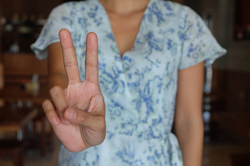 Close-up shot of unrecognizable woman make a peace sign while taking photo