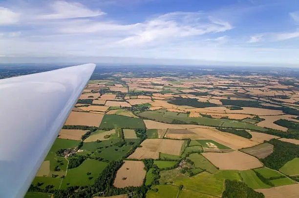 "Ariel landscape shot taken from the cockpit of a glider, part of the planes wing in the frame."