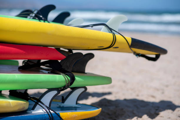 istock Set of different color surf boards in a stack by see. Surf boards for school on sandy beach. Soft toned photo. 1793041144