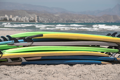 Set of different color surf boards in a stack by ocean. Surf boards for school on sandy beach. Soft toned photo High quality photo