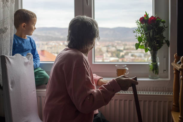 A female gardener in a red blouse is tending flowers near the window.