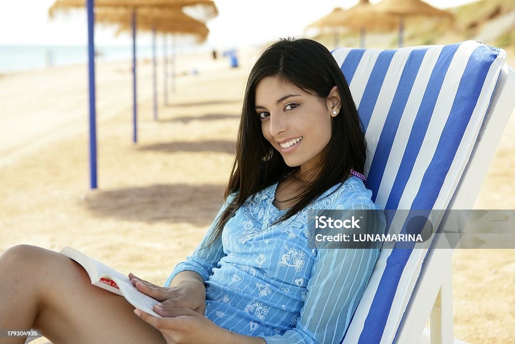 Linda mulher com um livro relaxante na praia - Foto de stock de 20-24 Anos royalty-free