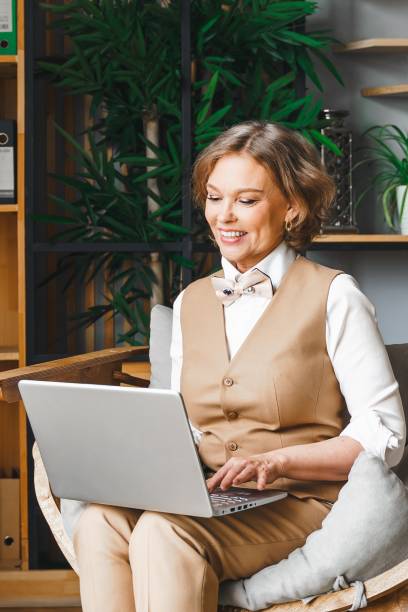 istock Confident stylish mature middle aged elderly woman in office.Workplace with laptop,using talking by mobile phone.General manager,ceo.Old senior businesswoman,60s lady in suit.Bank entrepreneur career 1793059173