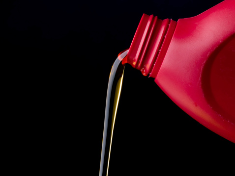 Oil Pouring from a red plastic bottle, isolated on black