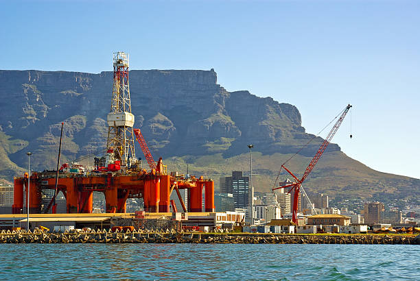 semi oleaginosi rig in bay in una grande città, vicino alla catena montuosa - oil rig oil sea mining foto e immagini stock