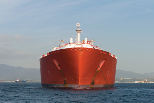 The large bows of a red gas ship anchored just off shore.Unsharpened.
