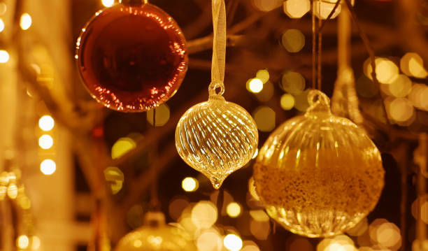 Stock image of Christmas baubles hanging & surrounded by out of focus Christmas lighting at night