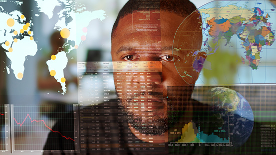 Stock Photograph of a black man, studying data on a see through screen. The data is associated with maps of the world, Earth.