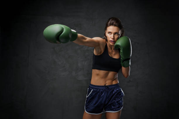 Female fighter in sports bra and boxing gloves showcases striking techniques stock photo