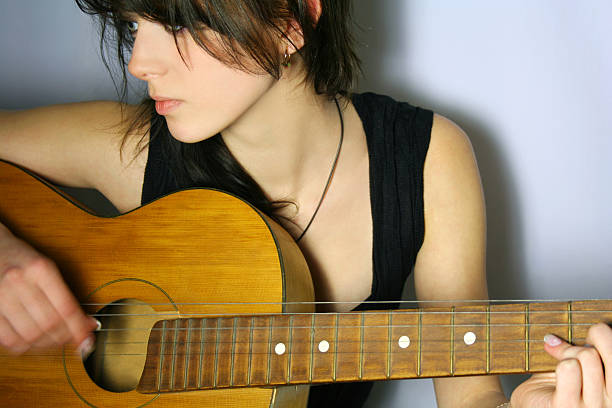 Portrait of girl in black singlet playing guitar stock photo