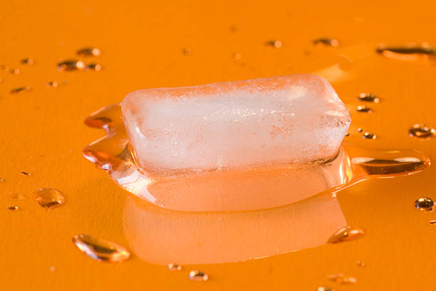 Icecube fondre avec des gouttelettes d'eau sur orange III - Photo