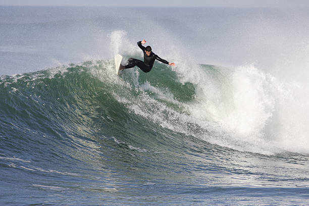 istock Man in black surfer gear and white board riding huge wave 179310240