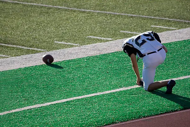 "Football player prays on the sidelines before a game. Color space is ProPhoto, RGB, processed from a 16 bit RAW image.View Similar Images Here:"
