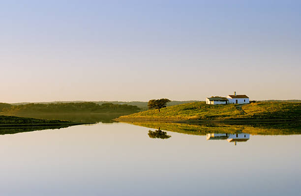Lone lake house standing on a hill by a still lake