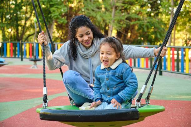 istock Happy Latin mother playing with her son on a swing in a park. 1793118065