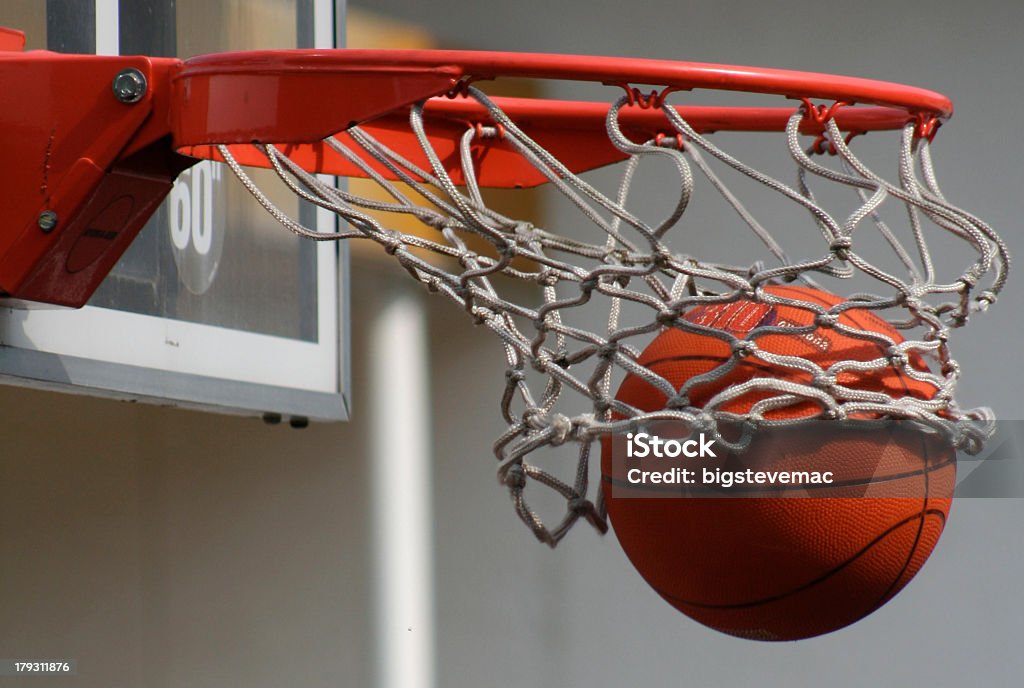 A basketball dropping through a net A basketball falls through a basket Basketball Hoop Stock Photo