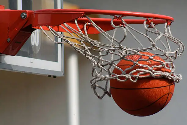 A basketball falls through a basket