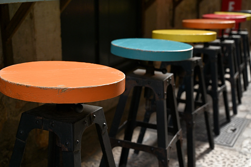 Different colored wooden and steel stools lined up in front of a counter