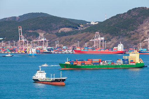 Busan, South Korea - March 22, 2018: Cargo ships sail the Busan bay on a sunny day
